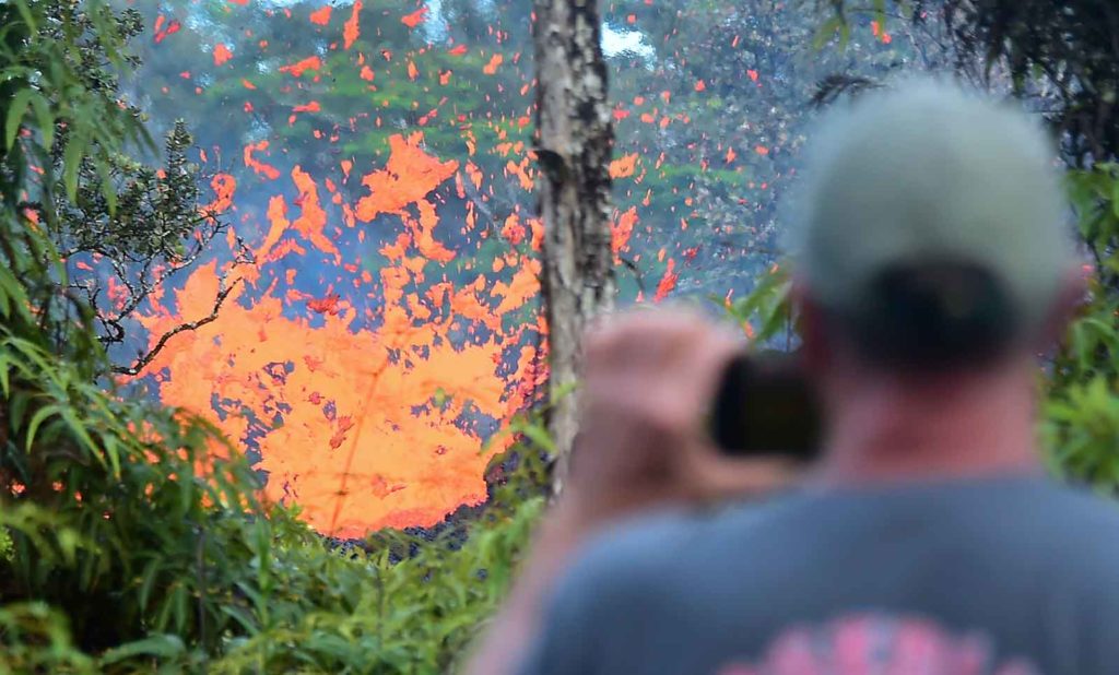 TOPSHOT - A man watches as lava is seen sewing from a fissure in the Leilani Estates subdivision near the town of Pahoa on Hawaii's Big Island on May 4, 2018 as up to 10,000 people were asked to leave their homes following the eruption of the Kilauea volcano that came after a series of recent earthquakes. (Photo by Frederic J. BROWN / AFP) (Photo credit should read FREDERIC J. BROWN/AFP/Getty Images)