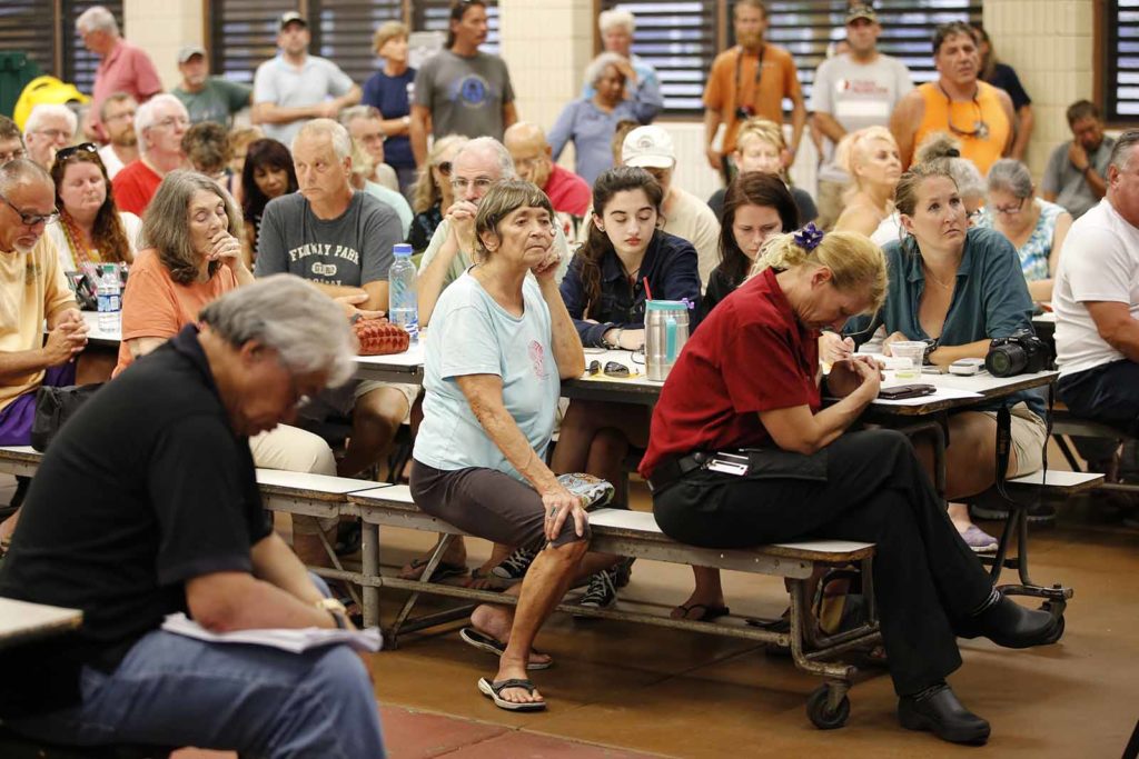 Residents from the lava affected areas of the Big Island hold a prayer before the start of a community meeting with local authorities at Pahoa High School, Friday, May 4, 2018, in Pahoa, Hawaii. (AP Photo/Marco Garcia)